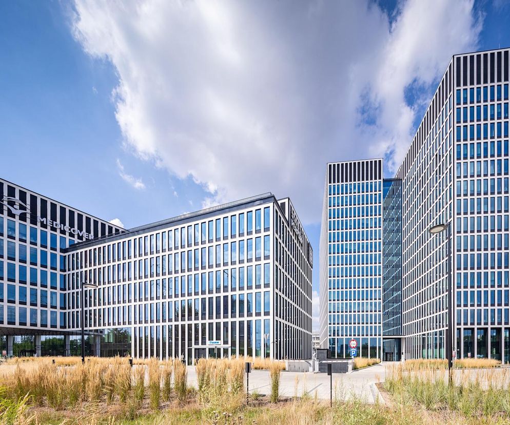 Nowoczesny zespół biurowo-usługowy Face2Face w Katowicach, z jasnymi elewacjami z spieków kwarcowych i ciemnymi glifami okien. Obiekt, zgłoszony do konkursu Życie w Architekturze 2025, oferuje zielony dziedziniec i jest przykładem zrównoważonej architektury. Więcej o takich projektach przeczytasz na Architektura Murator Plus.