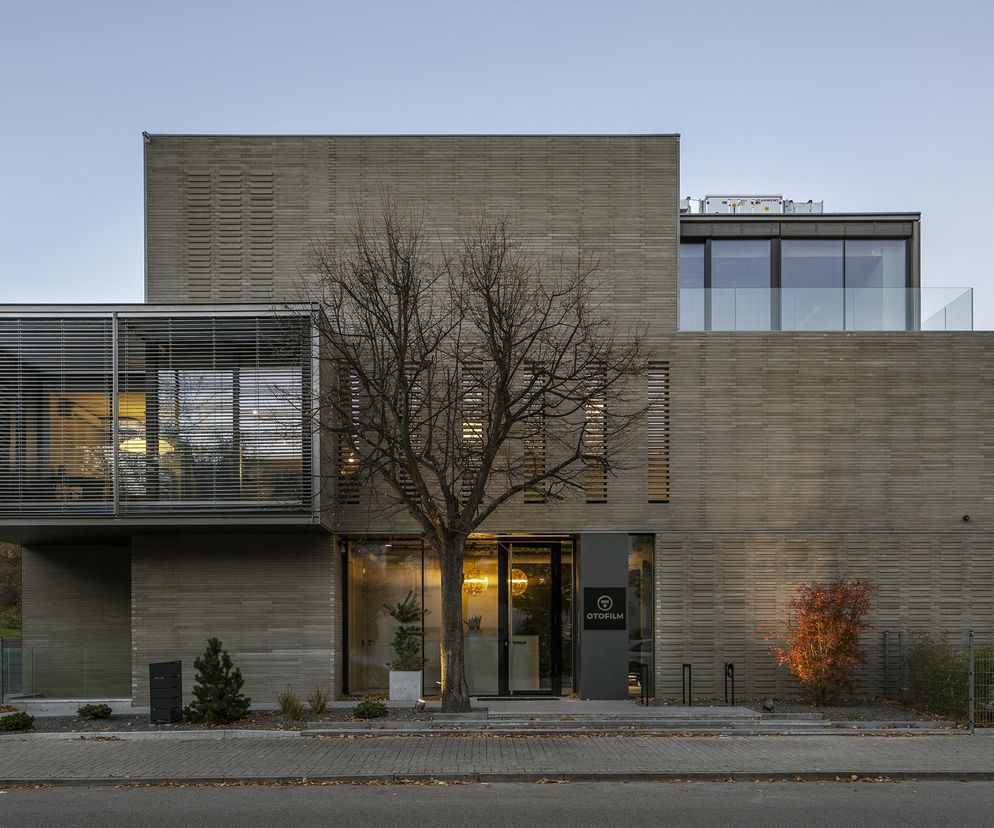 Willa pod Skocznią w Warszawie, autorstwa arch. Pawła Naduka, z fasadą z szarej cegły cementowej i przeszklonymi, poziomymi żaluzjami. Budynek posiada nowoczesne, kaskadowe bryły z tarasami, nawiązujące do modernistycznej architektury Mokotowa. Więcej o projekcie na Architektura Murator Plus.