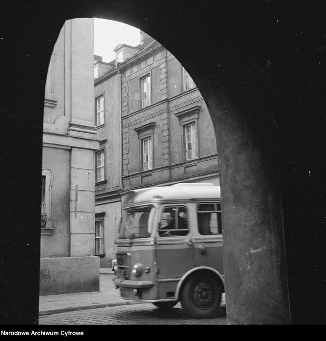 Widok spod arkady na zabytkowe kamienice na Starym Mieście. Widoczny także autobus San H100.