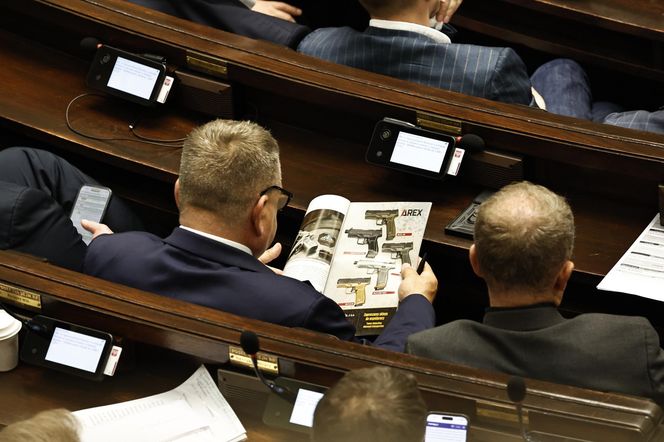 W  czasie obrad Sejmu poseł przeglądał katalog z bronią