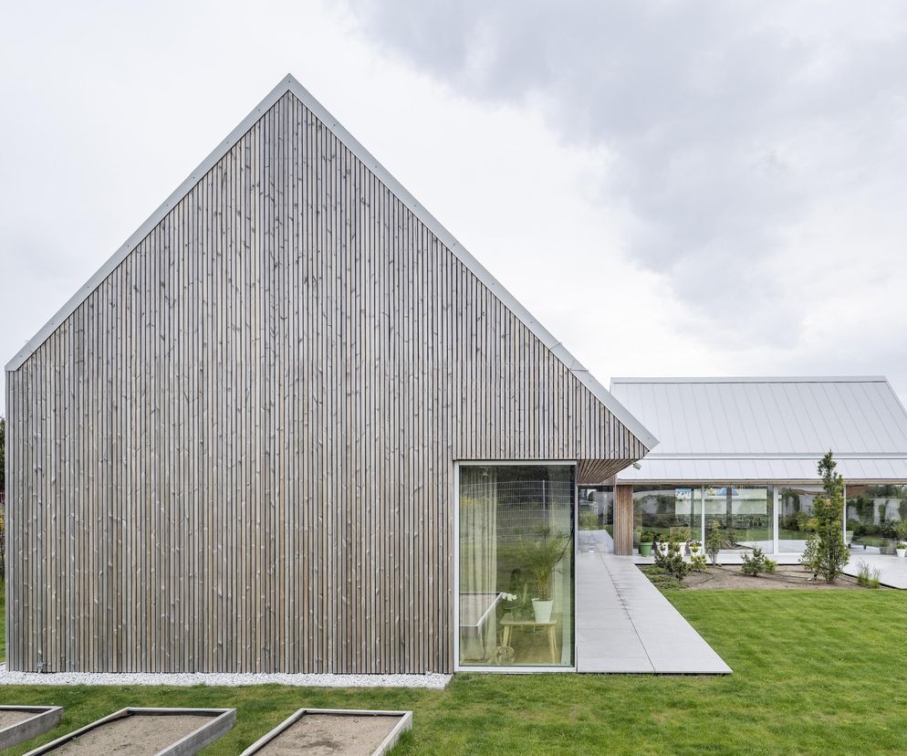 Nowoczesny dom jednorodzinny w Jastrzębiej Górze, autorstwa ARCHMONDO (Piotr Kowalczyk), z elewacją z pionowych desek świerkowych i dwuspadowym dachem. Projekt zakłada dużą przeszkloną powierzchnię, tworząc prywatny dziedziniec z tarasem, o którym więcej przeczytasz na Architektura Murator Plus.