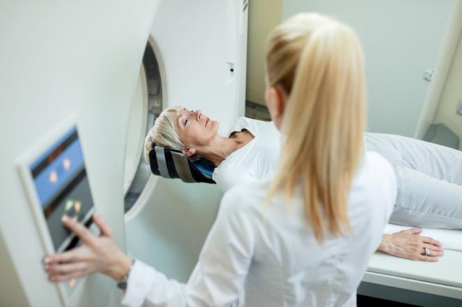 Dojrzała kobieta poddana badaniu tomografii komputerowej w szpitalu.