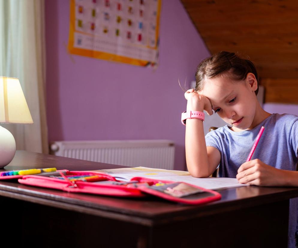 Dziewczynka siedząca przy biurku i odrabiająca lekcje