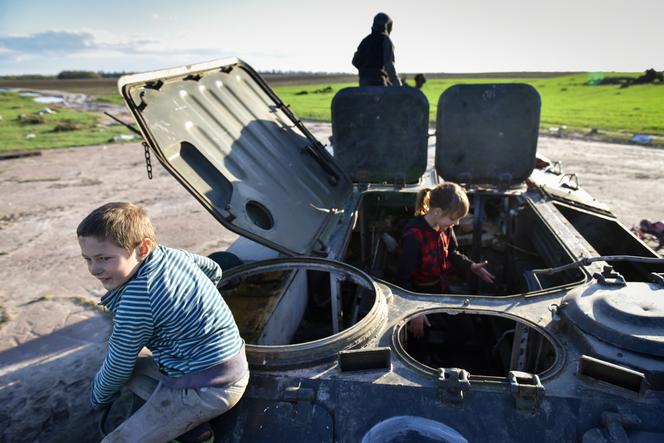 Dzieci bawiące się w zniszczonym rosyjskim transporterze