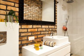 Jak urządzić wąską łazienkę? Biała łazienka z cegłą