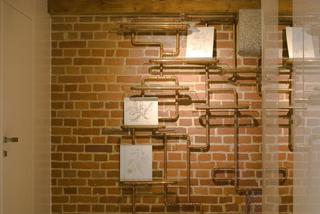 Widoczna instalacja elektryczna na ścianie z cegły i belki sufitowe w stylu industrialnym