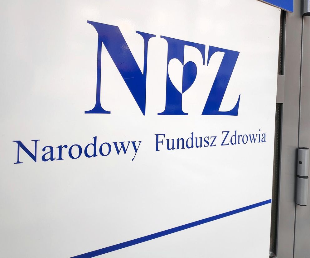 Napis NFZ Narodowy Fundusz Zdrowia w niebieskich literach na białej tablicy, symbol instytucji otrzymującej dodatkowe 1,3 mld zł na pokrycie nadwykonań w szpitalach. Więcej o finansowaniu NFZ i jego wpływie na służbę zdrowia znajdziesz na Super Biznes.