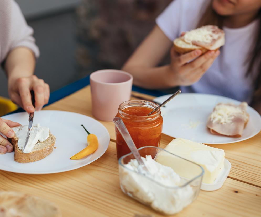 kobieta z córką przy śniadaniu, smaruje kanapkę serem