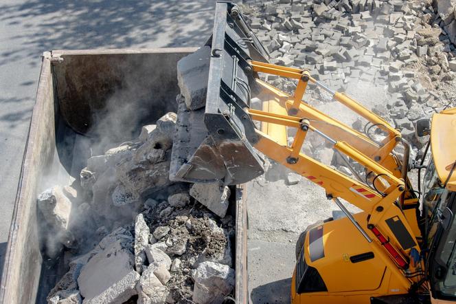 Koparka wyrzuca materiały budowlane do kontenera