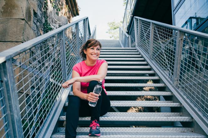 Kobieta odpoczywa na schodach po treningu