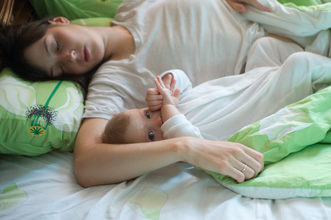 śpiąca kobieta z niemowlęciem w łóżku