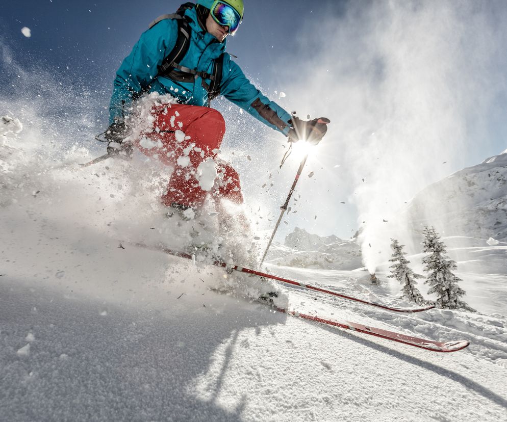Mężczyzna zjeżdża ze stoku narciarskiego. 