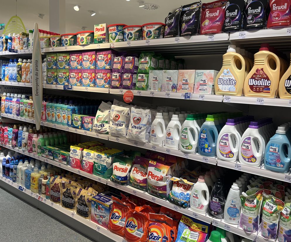 Alejka w drogerii z szerokim wyborem proszków i płynów do prania, w tym marek takich jak Denkmit, Persil i Lovela. Artykuł na Super Biznes informuje o niemieckich testach, które wykazały wysoką skuteczność tańszych produktów dostępnych w Polsce.