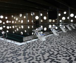 Wnętrze nowej pływalni w opolu - liczne okrągłe okna, mozaika szarych płytek na podłodze