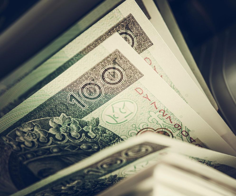 Banknoty studolarowe leżące w rzędzie, z widocznym nominałem i wzorami zabezpieczającymi, symbolizujące świadczenie pieniężne z MOPS na ekonomiczne usamodzielnienie. O szczegółach wsparcia przeczytasz na Poradnik Zdrowie.
