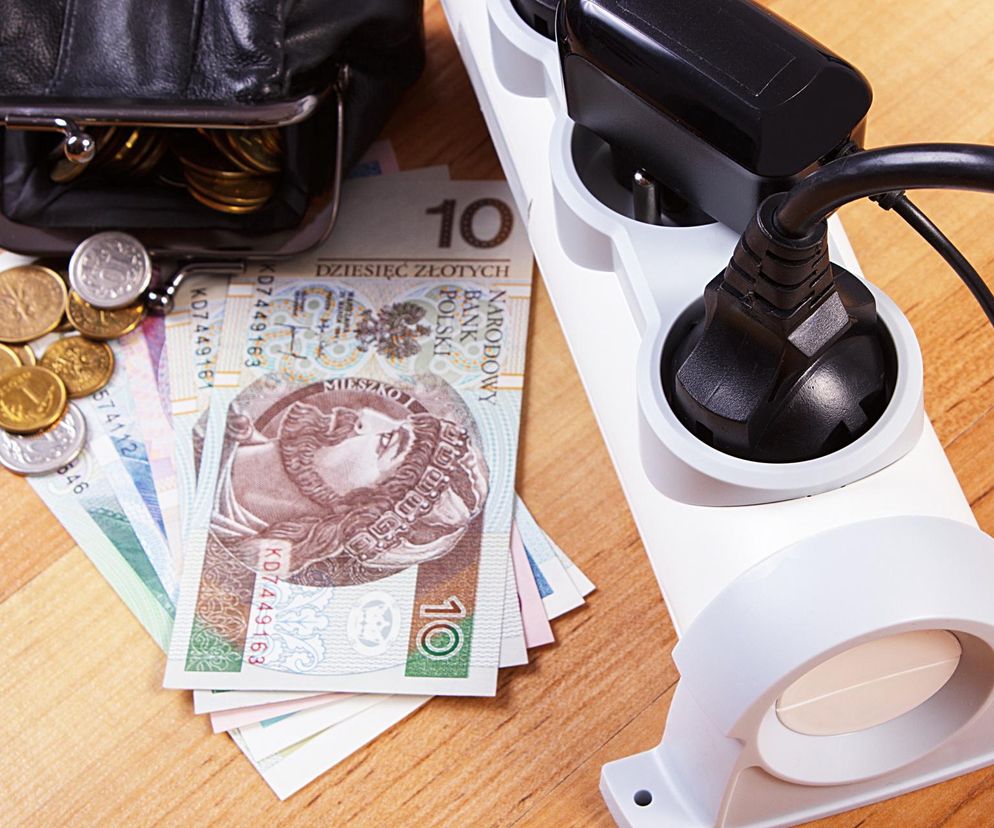 Portfel z monetami i banknotami oraz podłączona do listwy zasilającej wtyczka, symbolizujące koszty energii i możliwość oszczędzania. O ukrytych opłatach i dofinansowaniach na prąd przeczytasz na Super Biznes.