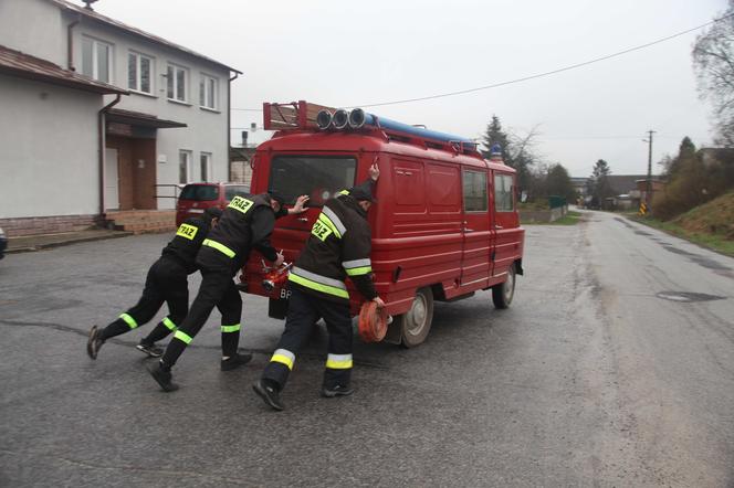 Strażacy pchają stary wóz strażacki, by dotrzeć do pożaru