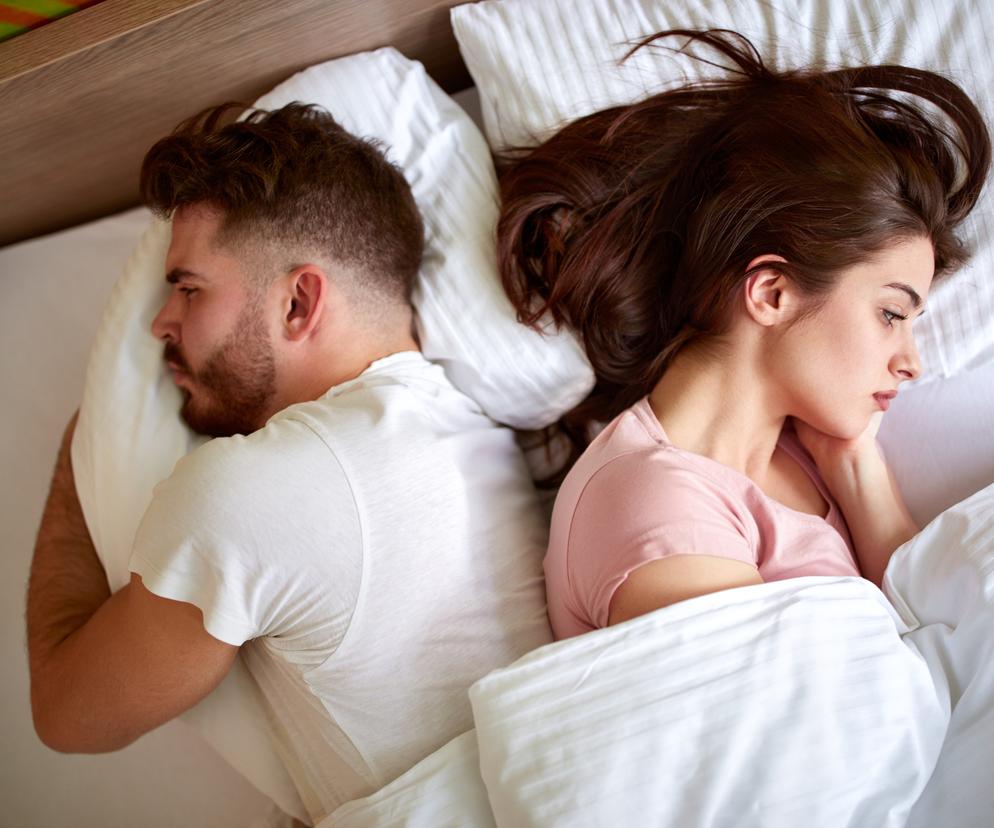 Pokłócona para leżąca w łóżku 