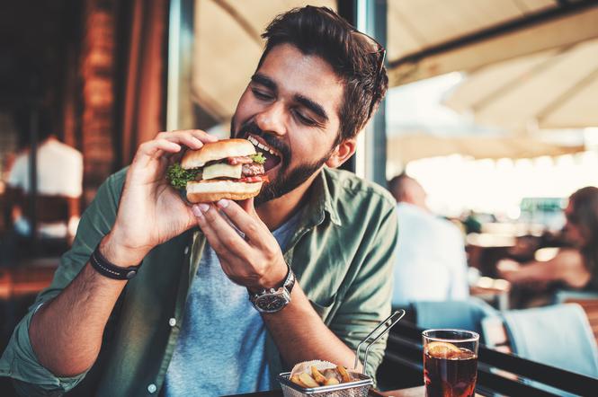 mężczyzna jedzący burgera w restauracji