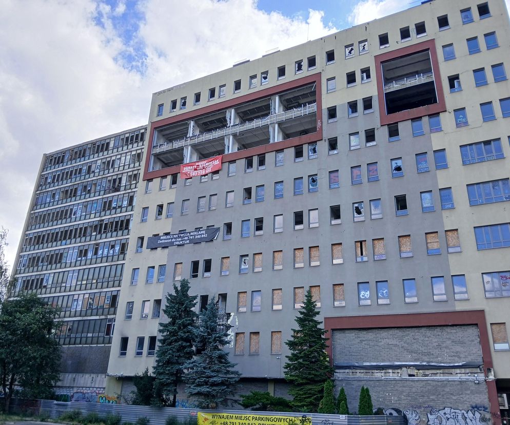 Opuszczony, zrujnowany budynek dawnej uczelni ALMAMER przy Wolskiej 43 w Warszawie. Fasada z wybitymi szybami, śladami ognia i graffiti, otoczenie zaniedbane, co podkreśla problematykę bezkarności w architekturze. Dowiedz się więcej na Architektura Murator Plus.