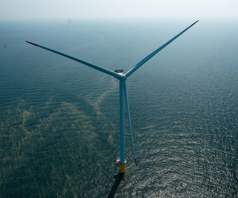 Morska farma wiatrowa Baltic Power na Bałtyku, z jedną turbiną w centrum kadru, prezentuje rozwój odnawialnych źródeł energii. Na horyzoncie widoczne inne instalacje. O inwestycjach ORLEN i środkach z KPO na budowę farm wiatrowych przeczytasz na Super Biznes.