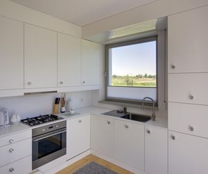 Kuchnia ma szafki wbudowane w ściany, dzięki czemu meble zlewają się z architekturą domu