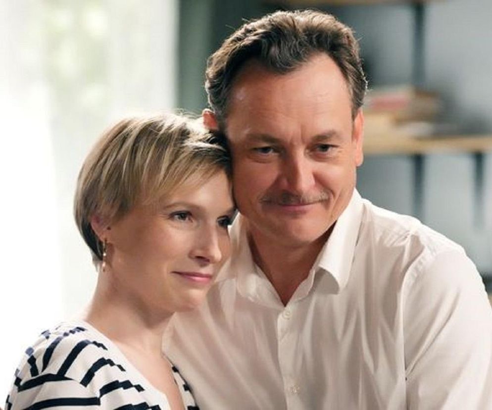 Aktorka Weronika Nockowska (Sonia) i Paweł Ławrynowicz (Robert Stefaniak) z Barw Szczęścia przytuleni, patrzą przed siebie z uśmiechem. Kobieta ma krótkie blond włosy i bluzkę w paski, a mężczyzna białą koszulę i wąsy. Więcej informacji o serialu znajdziesz na Super Seriale.