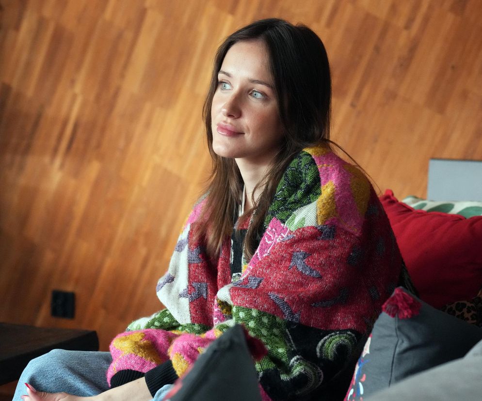 Natalia Sierzputowska jako Madzia w serialu „Barwy szczęścia siedzi na kanapie, otulona pledem w kolorowe wzory. Jej zamyślone spojrzenie odzwierciedla emocje związane z prowadzeniem fundacji dla ofiar przemocy seksualnej. Więcej o losach bohaterów na Super Seriale.