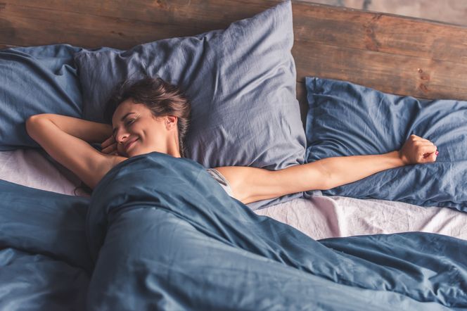 Kobieta przeciąga się w łóżku