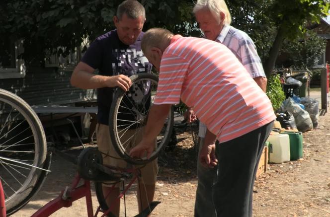 Rolnicy. Podlasie. Andrzej wymienia dziurawą dętkę w rowerze Gienka. Pomaga mu Sławek