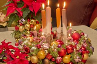 Adwentowa aranżacja: wieniec adwentowy i ozdobiony wazon z czerwoną poinsecją