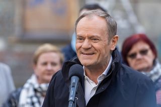 Tusk przed banerem o rekrutacji do służby więziennej. Nawiązuje do Celi plus