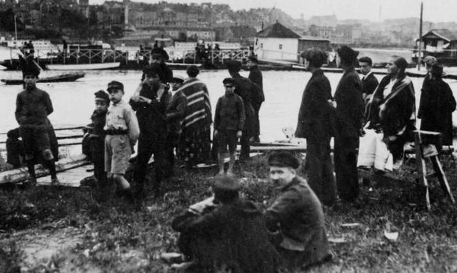 Grupa przechodniów obserwująca przypływ wody (1925)