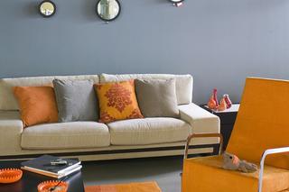 Szara kanapa z pomarańczowymi poduszkami