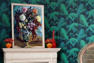 Modna tapeta z wzorem w palmy na ścianie kominkowej w salonie