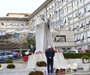 Wierni modlą się o zdrowie Franciszka przed pomnikiem Jana Pawła II. Składają kartki z życzeniami i wiązanki z białych róż