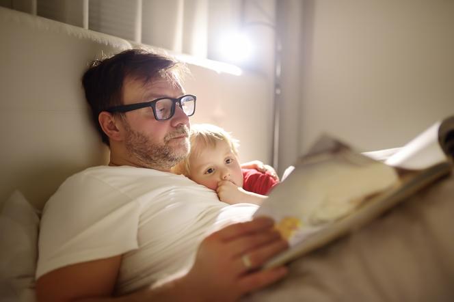tata czytający dziecku książkę w łóżku