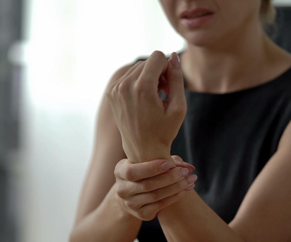 Młoda osoba z bólem ręki z powodu choroby reumatycznej