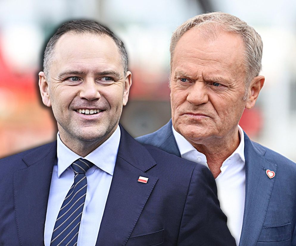 Karol Nawrocki uśmiecha się, mając za sobą Donalda Tuska z poważnym wyrazem twarzy. Nawrocki w granatowym garniturze z biało-czerwoną flagą wpiętą w klapę, Tusk również w garniturze. O decyzjach prezydenta przeczytasz na Super Biznes.