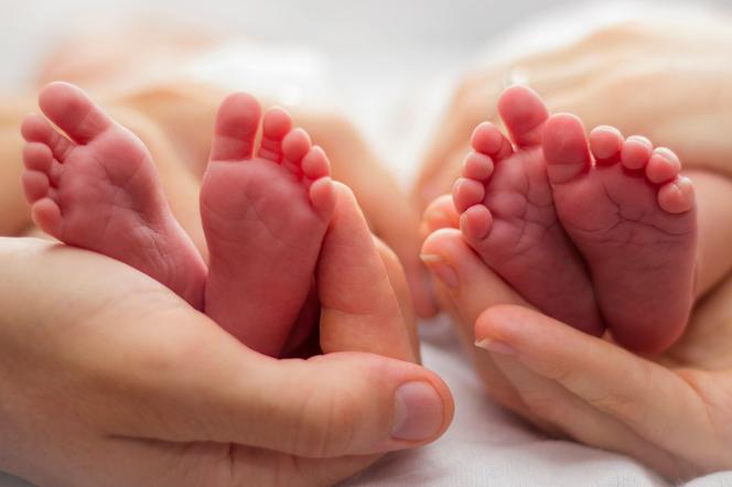 Stópki niemowląt w dłoniach dorosłych
