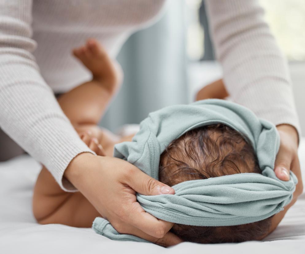 mama zakłądająca bluzeczkę przez głowę noworoka