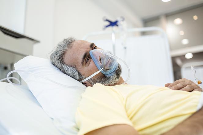 zbliżenie na mężczyznę, który leży na szpitalnym łóżku z powodu COVID-19