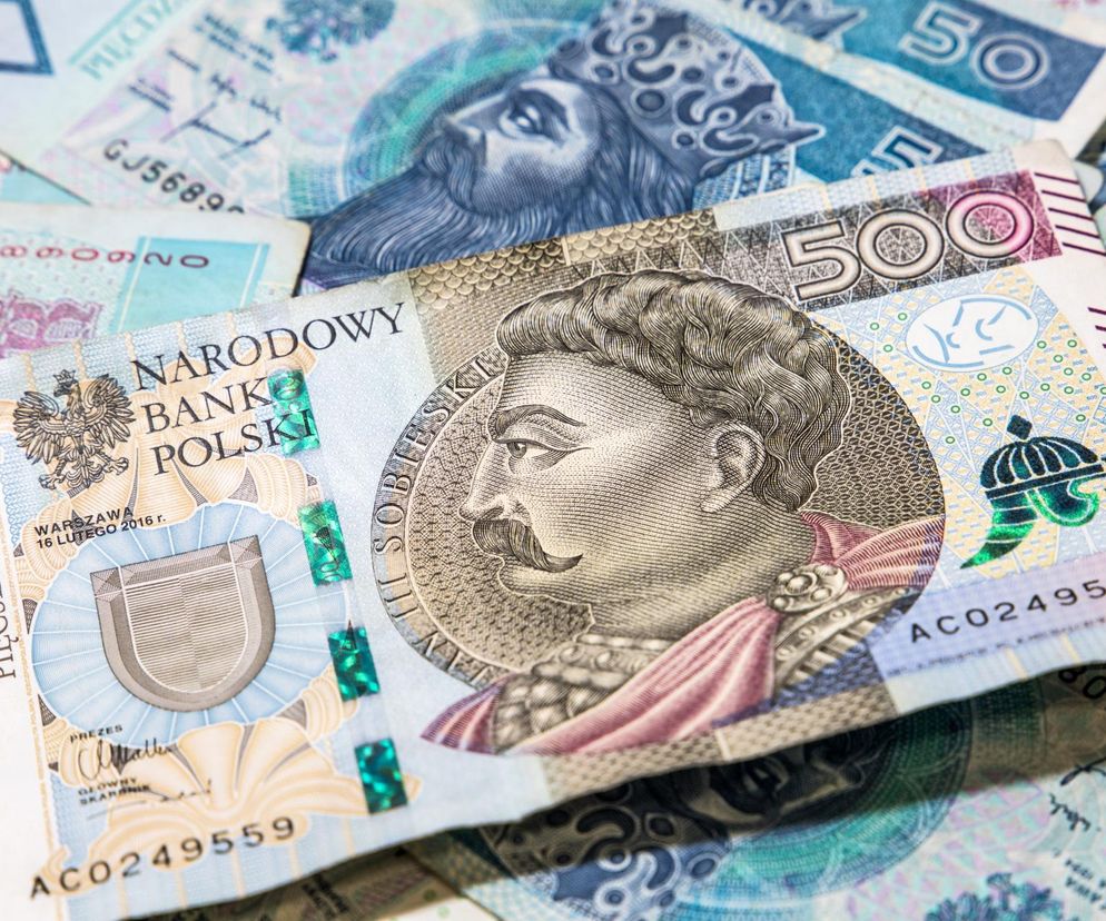 Banknot 500 złotych z wizerunkiem Jana III Sobieskiego, leżący na stosie innych polskich banknotów, symbolizuje finanse i inwestycje. Obraz nawiązuje do tematu podatku Belki i możliwości jego ominięcia, o czym przeczytasz na portalu Super Biznes.