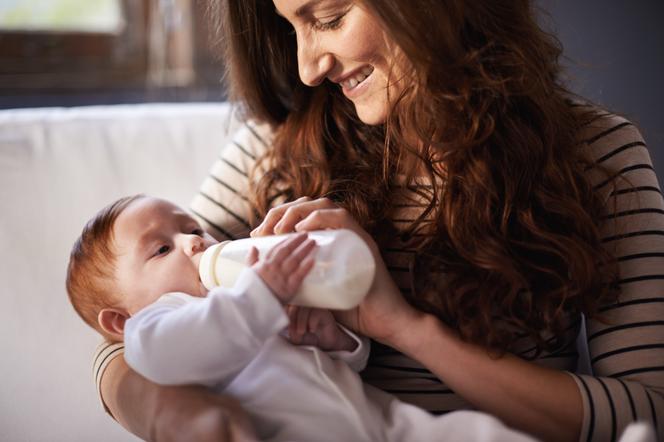 Kobieta karmi niemowlę butelką z mlekiem