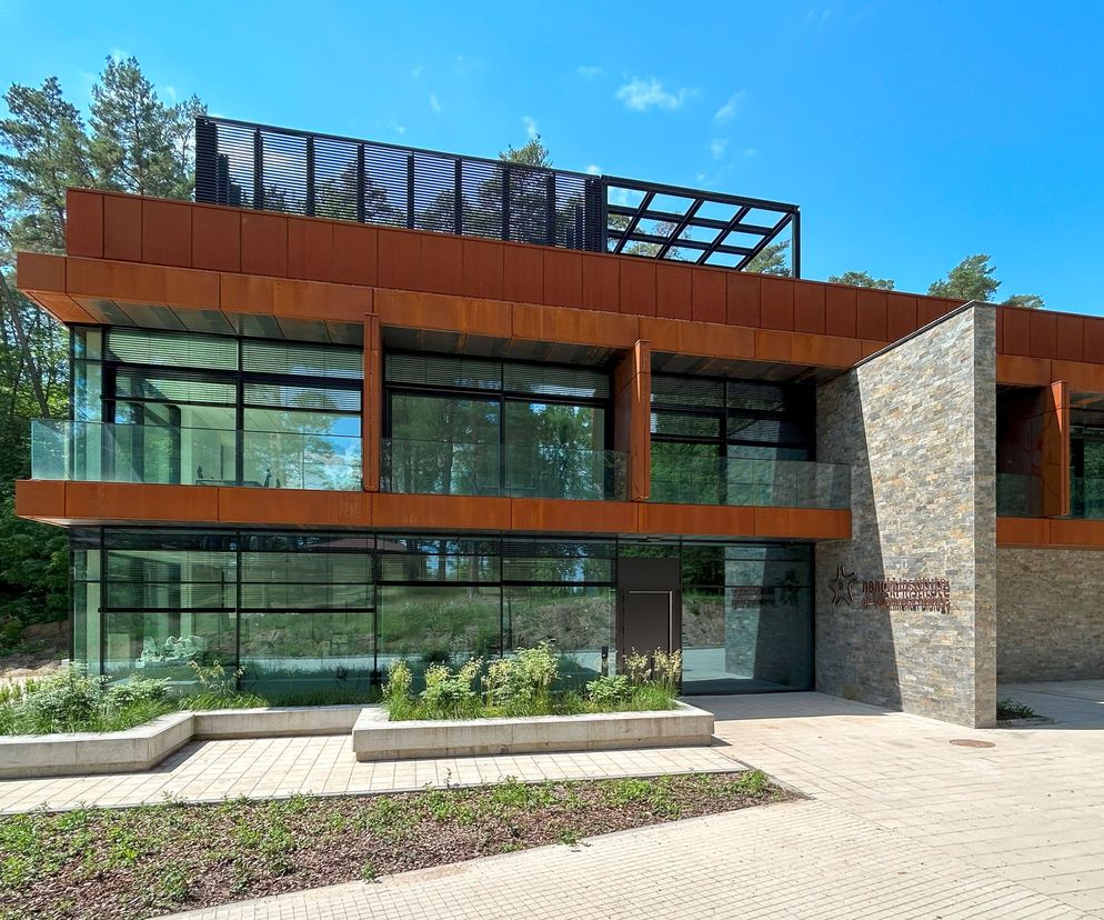 Nowoczesny budynek Krajowego Centrum Bioobrazowania BIOPIXEL z elewacją z paneli corten i kamienia, dużymi przeszkleniami, otoczony zielenią, harmonijnie wpisujący się w otoczenie. O projekcie przeczytasz na portalu Architektura Murator Plus.