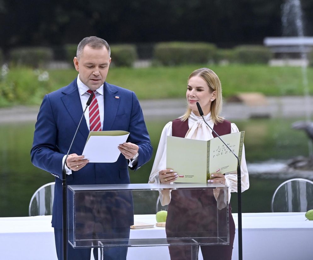 Marta Nawrocka, pierwsza dama, i Zbigniew Bogucki, szef Kancelarii Prezydenta, czytają z kartek podczas publicznego wystąpienia na tle fontanny. O ich roli i kwestii wynagrodzenia dla pierwszej damy przeczytasz na Super Biznes.