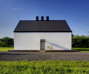 Drzwi wejściowe do domu to jedyna ozdoba północnej elewacji. Pokryto je zwykłymi deskami, a w kontraście do nich zawieszono futurystyczny daszek pełniący również funkcję lampy.