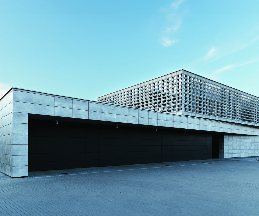 Nowoczesna poliklinika wyjazdowa dużych zwierząt w Olsztynie, autorstwa Doroty Szymaniak-Urban, charakteryzuje się fasadą z jasnych płyt i górną kondygnacją z ażurową, szarą siatką. Projekt, zgłoszony do konkursu Życie w Architekturze, łączy funkcjonalność z estetyką. Więcej o tej realizacji na Architektura Murator Plus.