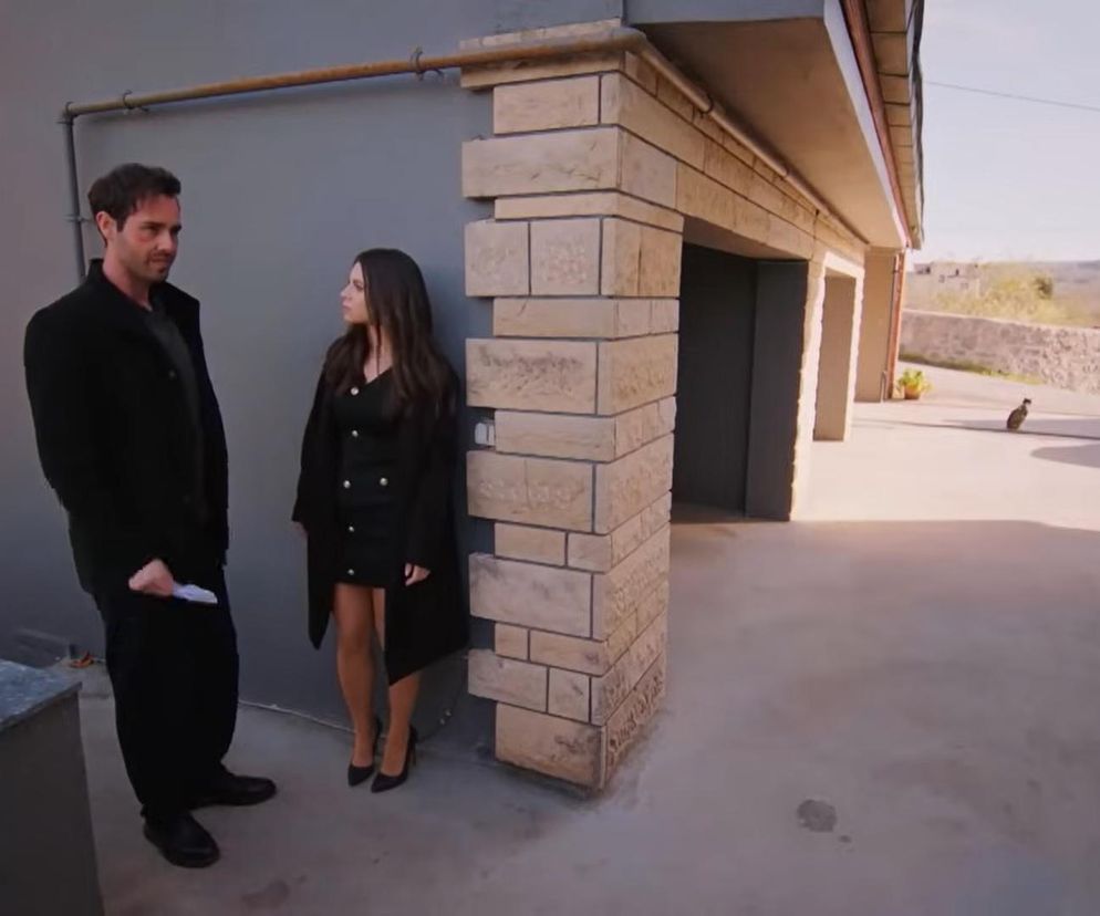 Acelya i Levent stoją na zewnątrz budynku. Acelya w czarnej sukience i płaszczu, Levent w ciemnym ubraniu. Scena z serialu Miłość i nadzieja odcinek 314, gdzie Acelya stawia warunki Leventowi. Więcej szczegółów na temat intryg i dramatów serialowych znajdziesz na stronie Super Seriale.