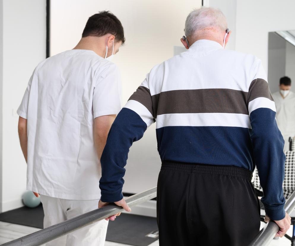 Fizjoterapeuta pomaga starszemu pacjentowi w rehabilitacji 